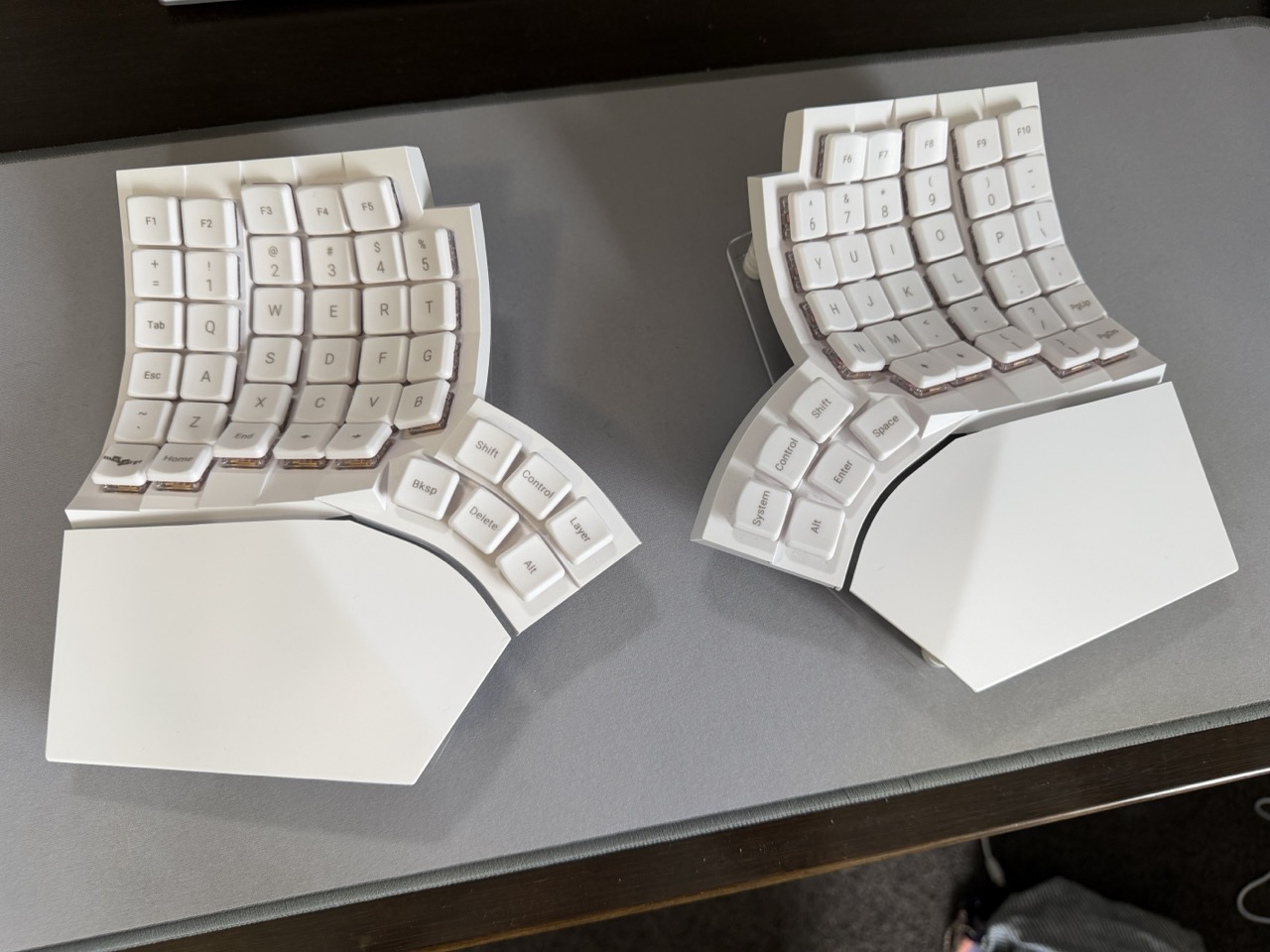Both halves of a white Glove80 split keyboard sitting on a grey deskmat